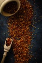 Top view red dried crushed hot chili peppers and chili flakes or powder in wooden spoon and bowl on grey rustic background, Royalty Free Stock Photo