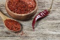 Top view red dried crushed hot chili peppers and chili flakes or powder in wooden spoon and bowl on wooden rustic background Royalty Free Stock Photo