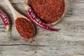 Top view red dried crushed hot chili peppers and chili flakes or powder in wooden spoon and bowl on wooden rustic background Royalty Free Stock Photo