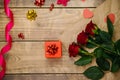 Top view, red gift box. Festive atmosphere, bouquet of red roses and bows on a wooden background Royalty Free Stock Photo