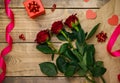 Top view, red gift box. Festive atmosphere, bouquet of red roses and bows on a wooden background Royalty Free Stock Photo