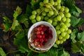 Top view of the red grapes  in the bowl next to the green grapes on the wooden surface Royalty Free Stock Photo