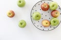 Top view of Red and green apples in white plate with black triangles pattern and apples on white background