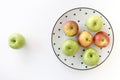 Top view of Red and green apples in white plate with black triangles pattern and green apple on white background Royalty Free Stock Photo