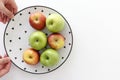 Top view of Red and green apples in white plate with black triangles pattern with hands on the left side with white background