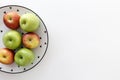 Top view of Red and green apples in white plate with black triangles pattern on the left side with white background