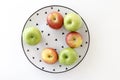 Top view of Red and green apples in white plate with black triangles pattern on white background