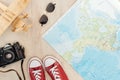 Top view of red gumshoes, film camera, toy plane, sunglasses and world map on wooden surface. Royalty Free Stock Photo