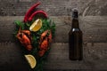 Top view of red lobsters, lemon slices, dill, pepper and bottle with beer on wooden surface. Royalty Free Stock Photo