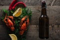 Top view of red lobsters, lemon slices, dill, pepper and bottle with beer on wooden surface. Royalty Free Stock Photo