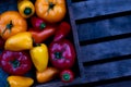 Top view of red and orange organic tomatoes with peppers inside old wooden box on wooden background Royalty Free Stock Photo