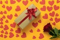 top view of a red rose lies on a yellow background. Lots of red cardboard hearts of different sizes. box packed in craft