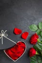 Red rose petals in a heart shaped box on a black background. Royalty Free Stock Photo