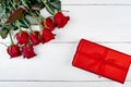 Top view of red roses and gift box on white wooden background, copy space. Greeting card mockup for Valentines Day, Womens Day Royalty Free Stock Photo