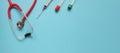 Top view of red stetoscope, syringe, and ampoules on blue background. Medicine concept. Banner size. Royalty Free Stock Photo