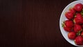 Top view red strawberries in a white plate on a wooden table Royalty Free Stock Photo