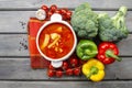Top view of red tomato soup on wooden table. Fresh vegetables ar