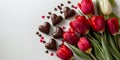 Top view of red tulips and chocolate heart shaped candies lying on light background. Royalty Free Stock Photo