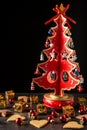 Top view of red wooden christmas tree with small pieces, on wooden table with gingerbread cookies, and red decorations, vertical,