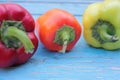 Red, yellow and orange bell peppers on light blue wooden background. Fresh summer or autumn vegetables harvest Royalty Free Stock Photo