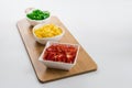 Top view of red, yellow, and peppers cut into cubes in white saucers on a wood cutting Royalty Free Stock Photo