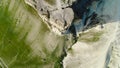 Top view of relief of surface of cliff. Shot. Dizzying top view of white cliff on background of green foot. Reliefs of