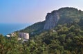 Top view of resort town with white buildings on shore of Black Sea bay among cliff mountains, blue water, summer, green forest Royalty Free Stock Photo