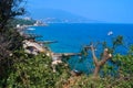 top view of resort town with white buildings on shore of Black Sea bay among mountains, blue water, green forest, broken trees Royalty Free Stock Photo