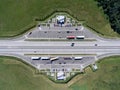 Top view at resting area of highway with parked trucks and passenger cars, a cafe and toilets