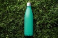 Top view of reusable steel thermo water bottle with mockup on green grass, aqua menthe color.