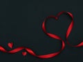 Top view of ribbon shaped as heart and red heart paper on black background with copyspace for valentine day, wedding