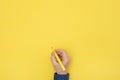 Top view right hand holding a pen yellow background