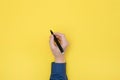 Top view right hand holding a pen yellow background