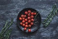 Top view of ripe cherry tomatoes with rosemary on black plate Royalty Free Stock Photo