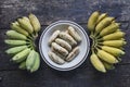 Ripe grilled banana dish and two hands of bananas on black floor Royalty Free Stock Photo