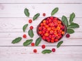 Top view of ripe red acerola cherries fruit in a ceramic bowl and green leaves on a wooden table. Royalty Free Stock Photo