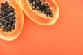 Top view of ripe tropical papaya halves with black seeds isolated on orange.