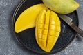 Top view. Ripe mangoes with yellow flesh in a black ceramic plate.