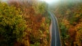 Top view of roadway with autumn colors. Aerial view of curvy road in beautiful foggy autumn forest Royalty Free Stock Photo