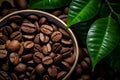 Top view of roasted coffee beans in a bowl, green leaves aside