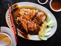 Roasted sliced duck or sliced Peking Duck on white plate with chopsticks and spicy sauce on dark background , chinese style food i Royalty Free Stock Photo