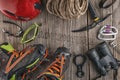 Top view of rock climbing equipment on wooden background. Chalk bag, rope, climbing shoes, belay/rappel device, carabiner and asce