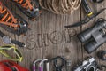 Top view of rock climbing equipment on wooden background. Chalk bag, rope, climbing shoes, belay/rappel device, carabiner and asce