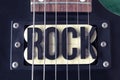 Top View of a ROCK lettering black word in middle of a six black electric guitar strings and yellow microphones Royalty Free Stock Photo