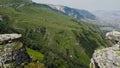 Top view of rocky cliffs above green mountain valley. Action. Beautiful landscape with high green mountains Royalty Free Stock Photo