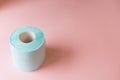 Top view roll of blue toilet paper on pink background copy space