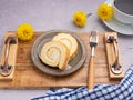 Top view of roll cake on a plate on a wooden tray with a cloth and a white coffee cup. Royalty Free Stock Photo
