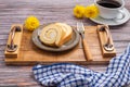 Top view of roll cake on a plate on a wooden tray with a cloth and a white coffee cup on a wooden table. Royalty Free Stock Photo