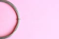 Top view of a roll of a metal wire on a pink background