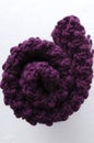 Top view of rolled dark purple knitting fabric on the white surface